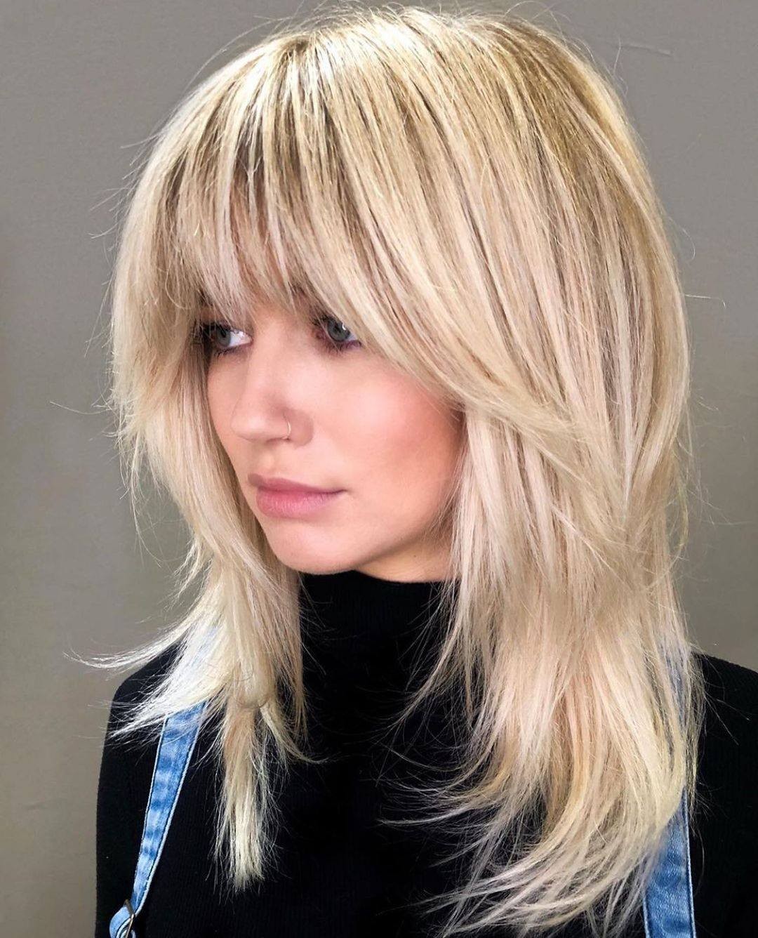 1. Feathered Blonde Shag with Full Fringe - Medium-Length Hairstyle Ideas for Women